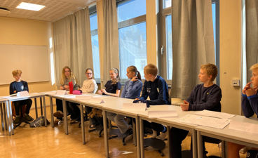 en gruppe mennesker som sitter ved bord