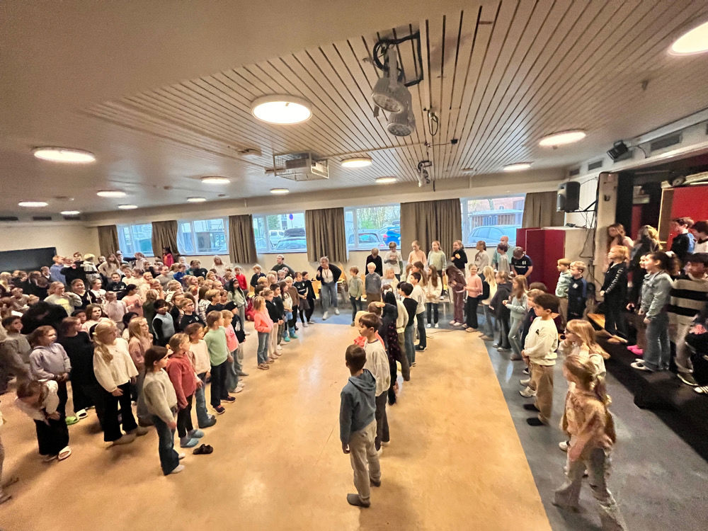 En stor gruppe mennesker i et stort rom med store skjermer