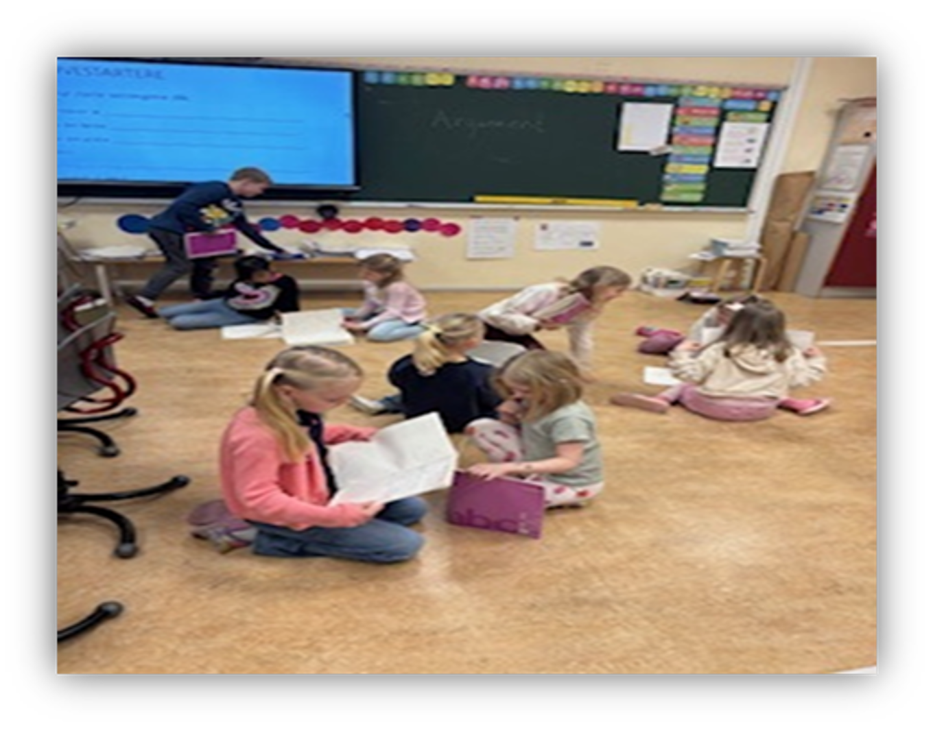 en gruppe barn som sitter på gulvet foran en skjerm