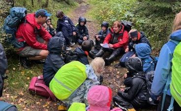 En gruppe mennesker som sitter på bakken i skogen