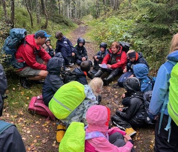 En gruppe mennesker som sitter på bakken i skogen